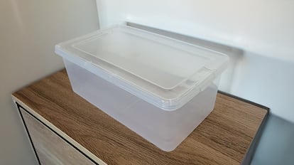 Cajas de plástico para almacenamiento sobre una mesa de madera.