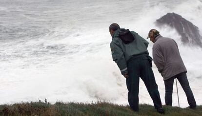 Dos personas se asoman al acantilado de Punta Langosteira (A Coru&ntilde;a), en el que una ola se trag&oacute; el lunes a tres personas. 