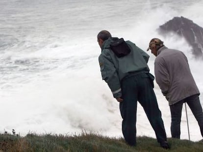 Dos personas se asoman al acantilado de Punta Langosteira (A Coru&ntilde;a), en el que una ola se trag&oacute; el lunes a tres personas. 