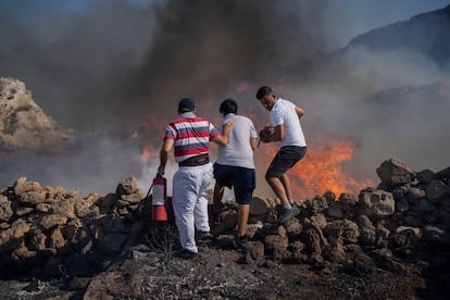 Local residents try to extinguish a fire, near the seaside resort of Lindos, on the Aegean Sea island of Rhodes, southeastern Greece, on July 24, 2023