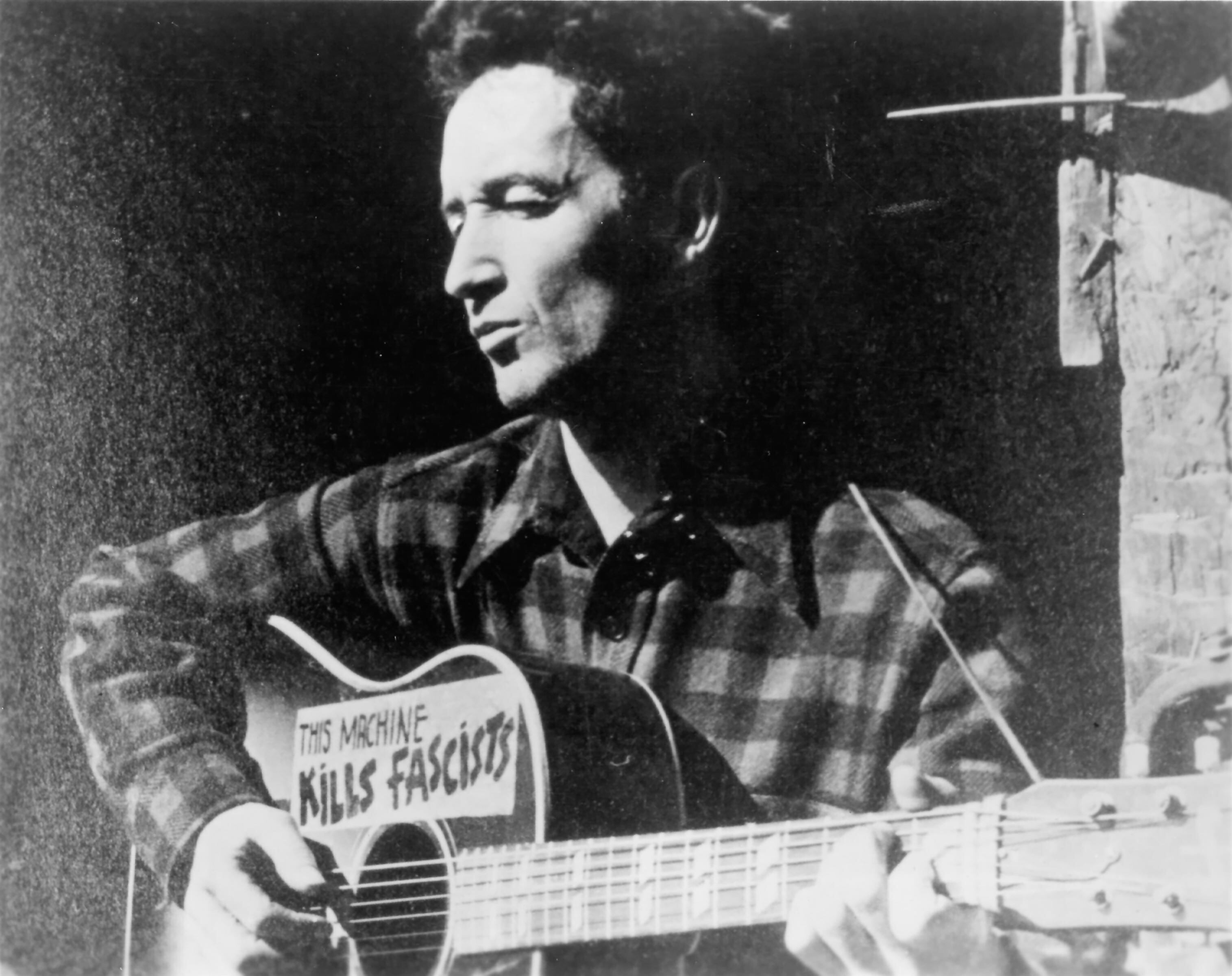 El cantautor Woody Guthrie, alrededor de 1940, con su célebre guitarra en la que se lee: 'Esta máquina mata fascistas'.