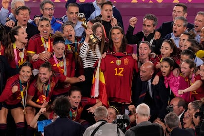 La reina Letizia sostiene la camiseta de la selección con su nombre, acompañada de la infanta Sofía (que muestra la Copa del Mundo) y el resto de las jugadoras y el equipo técnico.
