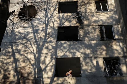 Una mujer retira una ventana rota en uno de los edificios alcanzados por el ataque ruso, este domingo. 