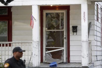 Un miembro de la policía pasa junto a la puerta rota de una casa en la Avenida Seymour, en el barrio de Cleveland, Ohio (EE UU), donde fueron halladas tres jóvenes desaparecidas.