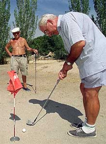 Eusebio Sanz y Cándido Fernández (con camisa) juegan al golf en un terreno del polideportivo de Pan Bendito.
