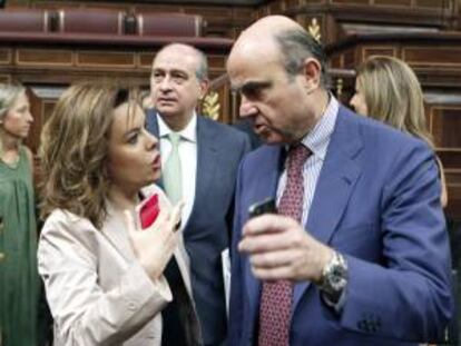 La vicepresidenta del Gobierno, Soraya Saénz de Santamaría, iz, y el ministro de Economía, Luis de Guindos, d, conversan en el hemiciclo de Congreso de los Diputados. EFE/Archivo