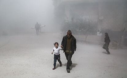 Un hombre y una nieta huyen después de un ataque aéreo en Ghouta, Damasco.