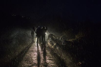 Refugiados esperan bajo la lluvia un autobus en el la isla griega de Lesbos para ser transladados a un centro.