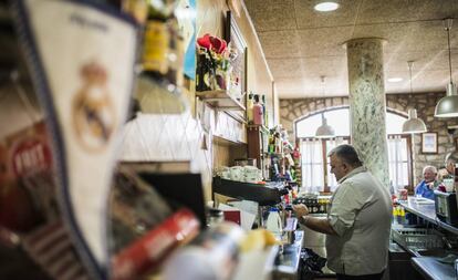 La banderola del Reial Madrid a la barra del Casal d'Alfés, l'únic restaurant del poble. Al fons, el seu encarregat, Gregorio Pifarré, un dels tres madridistes dels 300 habitants prepara un cafè per als seus clients.