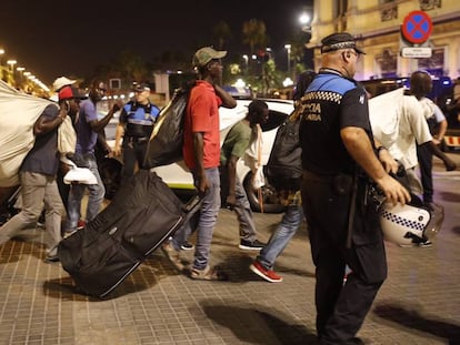 Un grupo de manteros ayer, vigilados por la polic&iacute;a portuaria