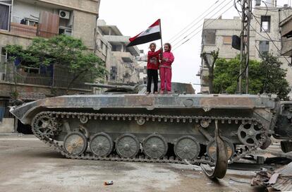 Niñas sirias sujetan una bandera del país sobre un tanque en Hazzeh, Guta Oriental (Siria).