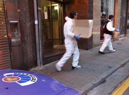 Agentes de la Ertzaintza salen del edifico de la localidad vizcaína donde ha sucedido el presunto homicidio.