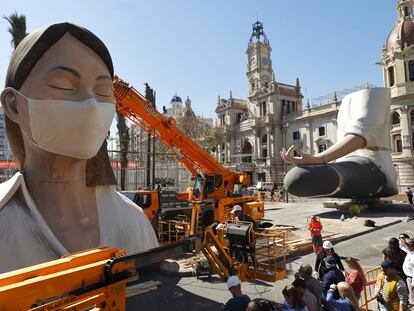 Operarios colocan una mascarilla a la falla del Ayuntamiento, este miércoles en Valencia.