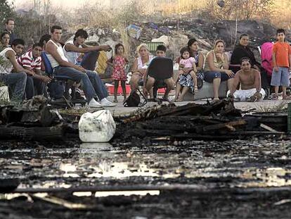 Una familia afectada por el incendio mira las cenizas de sus infraviviendas en el poblado de Fuencarral.