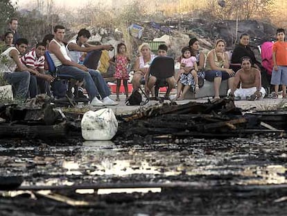 Una familia afectada por el incendio mira las cenizas de sus infraviviendas en el poblado de Fuencarral.