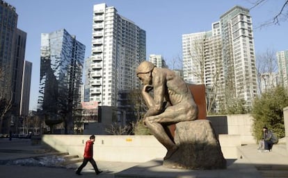 Un hombre pasa frente a una estatua en un distrito de negocios del centro de Pekín.
