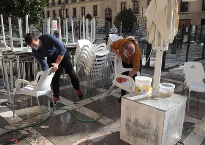 Dos hombres preparan la terraza del bar Torres Bermejas en Plaza Nueva de Granada, este lunes.