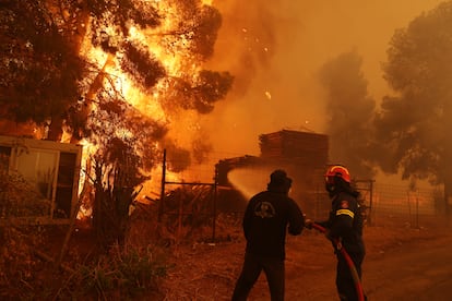 Bomberos rocían agua para apagar el incendio en la localidad de Nea Penteli, cerca de Atenas, este martes. 