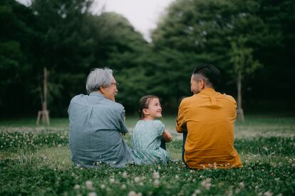 Una niña junto a su padre y a su abuelo en un parque.