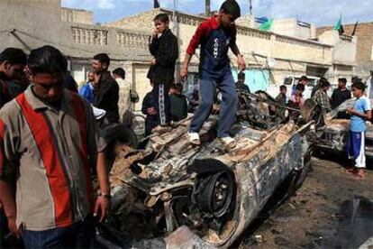 Varios niños juegan alrededor de los restos de un coche calcinado por un mortero en Baghdad.