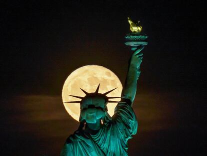 A supermoon is seen behind the Statue of Liberty in New York, in June 2022.