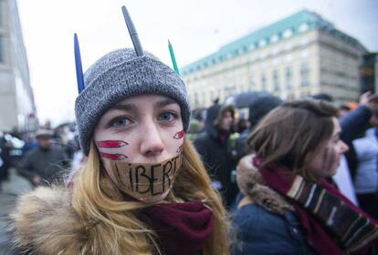 Una mujer se tapa la boca con la palabra 'Libertad' y se pinta la cara con lápices, en homenaje a los dibujantes asesinados en París.