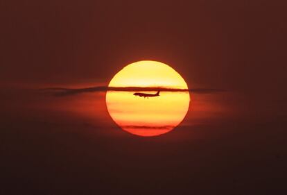 Un avión se 'funde' con el sol mientras sobrevuela la Bahía de Panamá durante el amanecer.