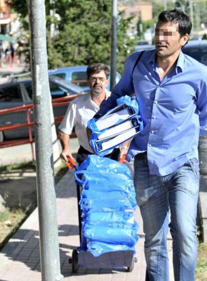 Un policía y un conserje transportan los documentos intervenidos en el Ayuntamiento de Boadilla.