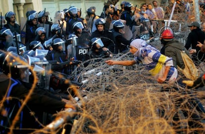 Un manifestante habla con policías antidisturbios que protegen el palacio presidencial de El Cairo.