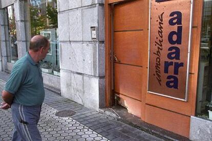 Un peatón observa esta mañana la puerta de la inmobiliaria Adarra, destrozada por la bomba.