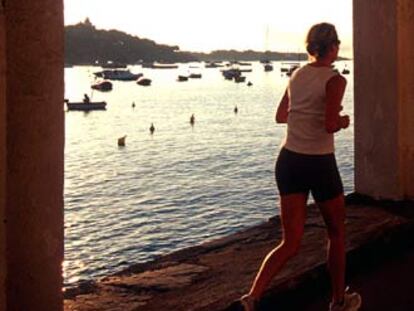 Una mujer corre al borde del mar en Cadaqués (Girona).