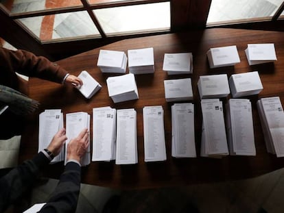 Dos personas escogen papeletas para votar en un centro electoral de Barcelona.