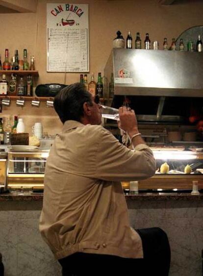 Un hombre bebe en la barra de un bar.