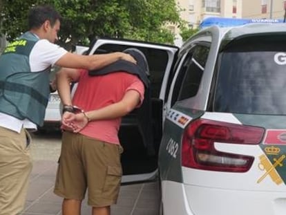 Un guardia civil conduce al detenido por la agresión de Umbrete.