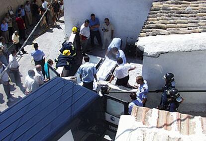 Trabajadores de los servicios funerarios sacan de la casa los cuerpos de las víctimas del incendio.