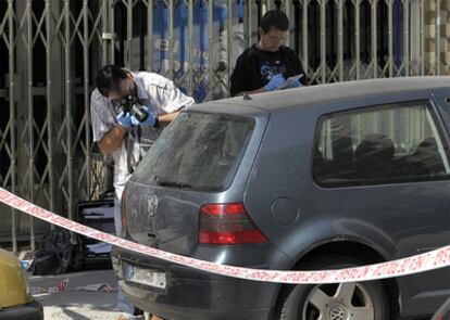 Un policía toma imágenes en el lugar donde esta el cadáver, en la calle de San Luis, en Alcorcón.