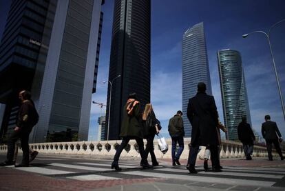 Varios peatones pasan junto a las cuatro torres de la Castellana.