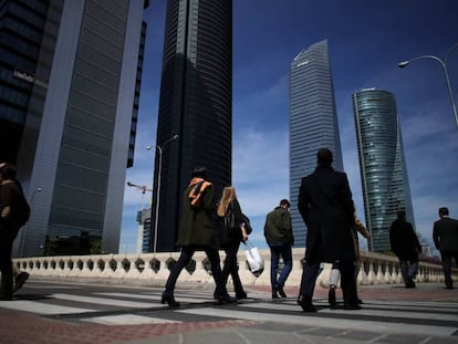 Varios peatones pasan junto a las cuatro torres de la Castellana.