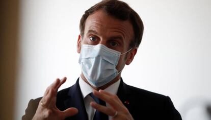 El presidente francés Emmanuel Macron protegido por una máscara facial habla con trabajadores sanitarios en una visita a un centro médico de Paris