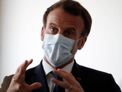 El presidente francés Emmanuel Macron protegido por una máscara facial habla con trabajadores sanitarios en una visita a un centro médico de Paris