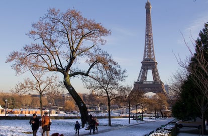 Unos turistas caminan por el parque nevado próximo al Trocadero, junto a la Torre Eiffel de París, Francia, el día después de la fuerte nevada.