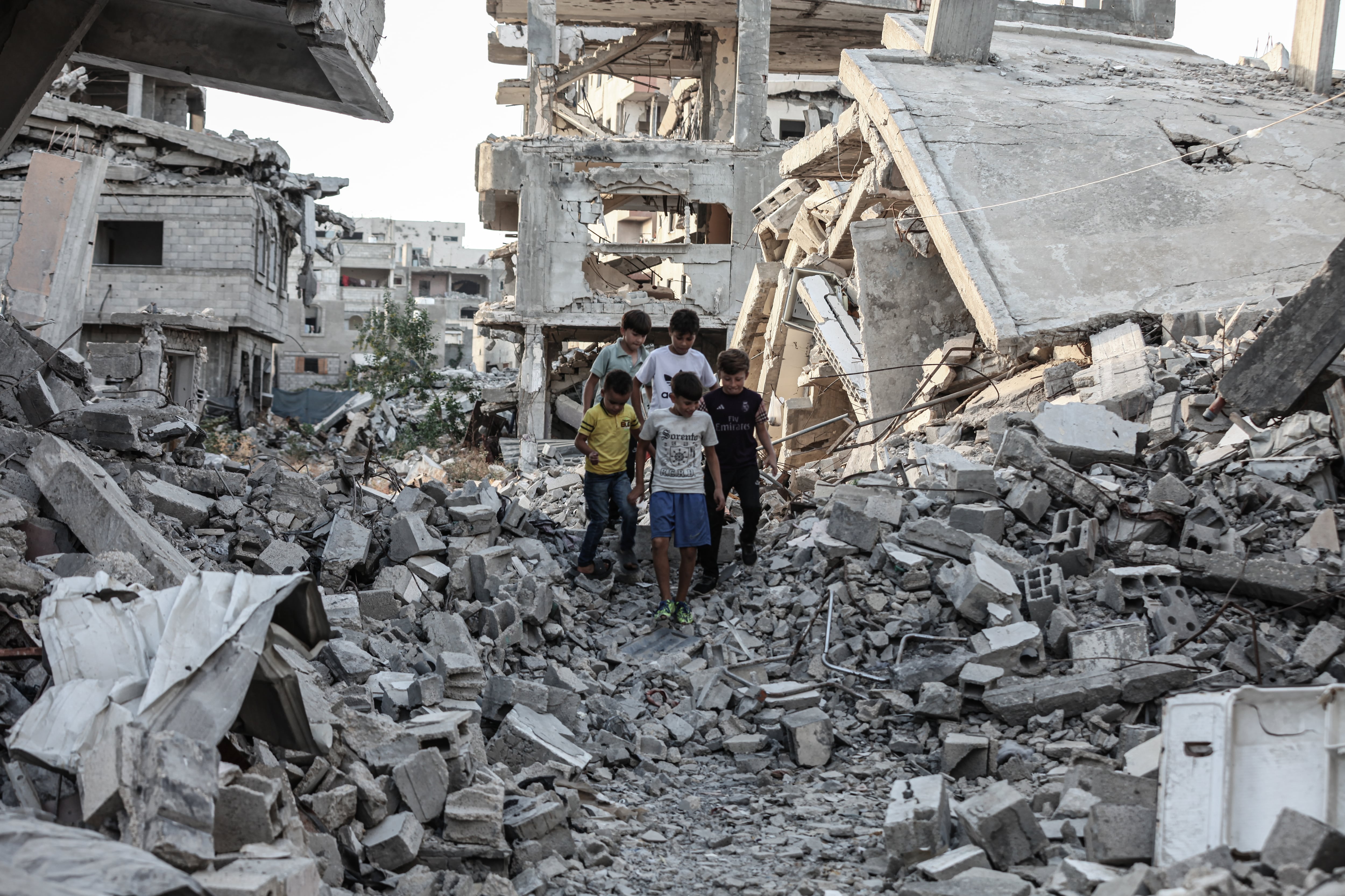 Niños caminan entre los escombros de edificios destruidos por las bombas en Deir el Balah, este sábado. 