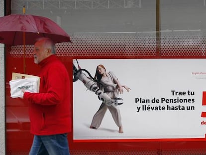 Una persona pasa delante de un anuncio de planes de pensiones.