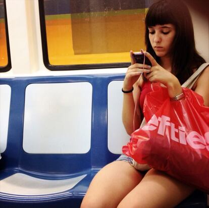 Una usuaria se conecta a internet con su m&oacute;vil en un vag&oacute;n del metro de Madrid.
