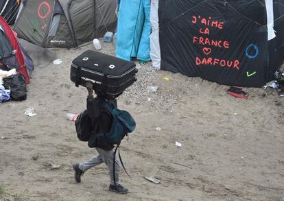 Un migrante camina con su equipaje hacia el punto de encuentro establecido por las autoridades para ser evacuado del campo de Calais (Francia). 