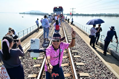 Un turista se hace un selfie junto al popular "tren flotante" en una parada en un puente de la presa Pasak Jolasid, Tailandia.