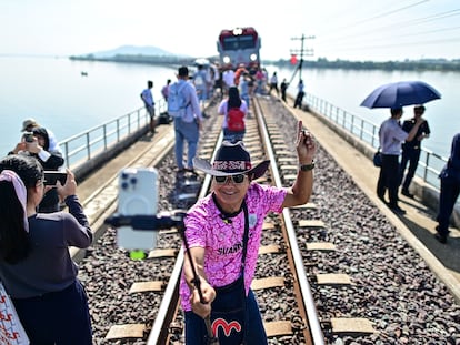 Un turista se hace un selfie junto al popular "tren flotante" en una parada en un puente de la presa Pasak Jolasid, Tailandia.