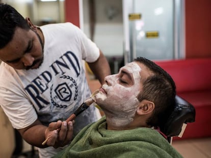Aasif Khalifa aplica una máscara blanqueadora a su cliente Himesh Dhulab en su salón de belleza de Johannesburg (Sudáfrica), el 3 de agosto de 2018.