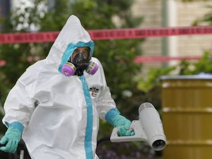 A hazmat worker cleans outside the apartment building of the infected hospital employee on Sunday.