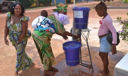 Un grupo de mujeres guineanas se lavan las manos en la entrada del hospital de Kipe.